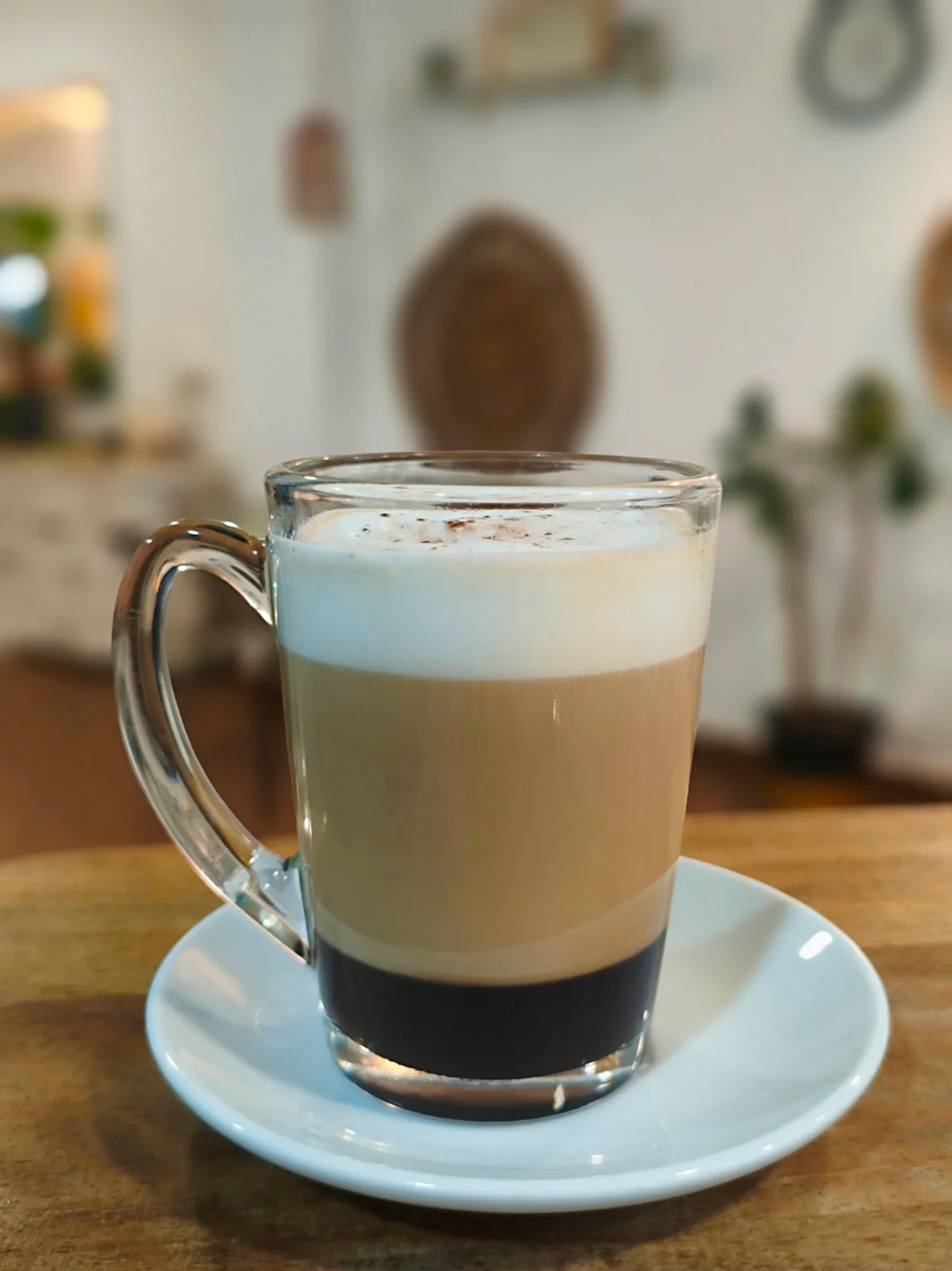 Vaso de café con leche mediano con espuma servido en taza de cristal en La Nonna Brunch, en el centro de Figueres
