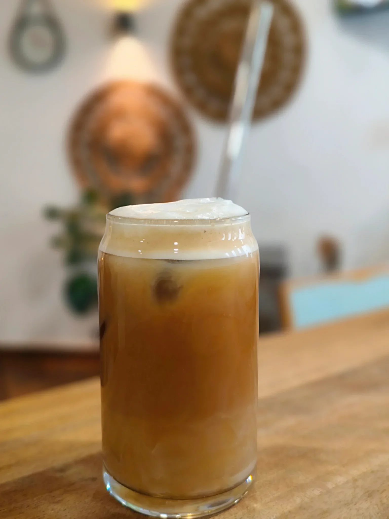 Café con leche con hielo en vaso tipo lata sobre la barra de madera de La Nonna Brunch, en Figueres