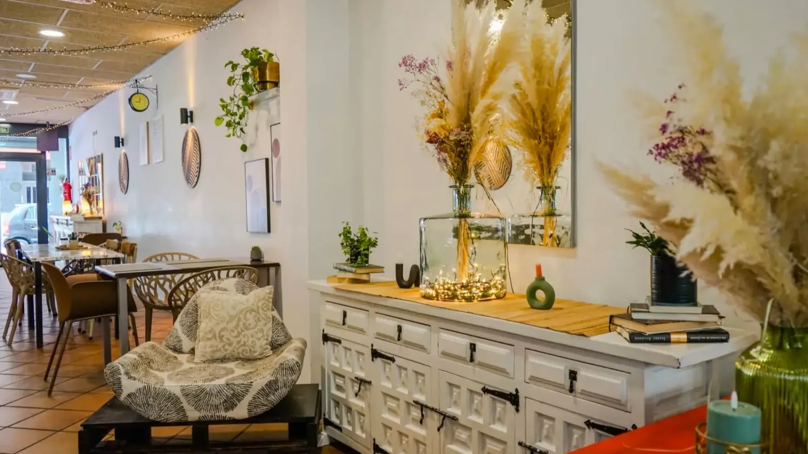 Rincón acogedor del interior de La Nonna Brunch en Figueres, con sillón, plantas y decoración cálida en madera y tonos blancos