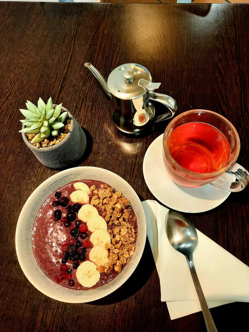 Açaí bowl con plátano, frutos rojos y granola junto a té caliente en mesa de La Nonna Brunch en Figueres
